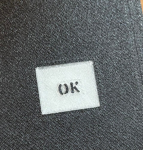 Exterior view of the 3D-printed enclosure with the power off. The surface is completely smooth and seamless, with the "OK" label subtly visible through the transparent filament window, highlighting the high-quality finish of the multi-material print